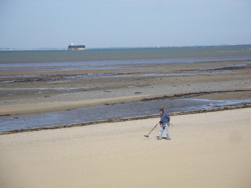 A detectorist at the water's edge on Ryde beach, Isle of Wight